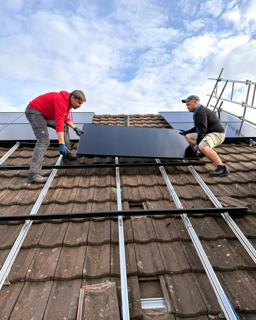 Zwei Läbesruum-Mitarbeiter montieren Solarpanels auf einem Dach in Winterthur.