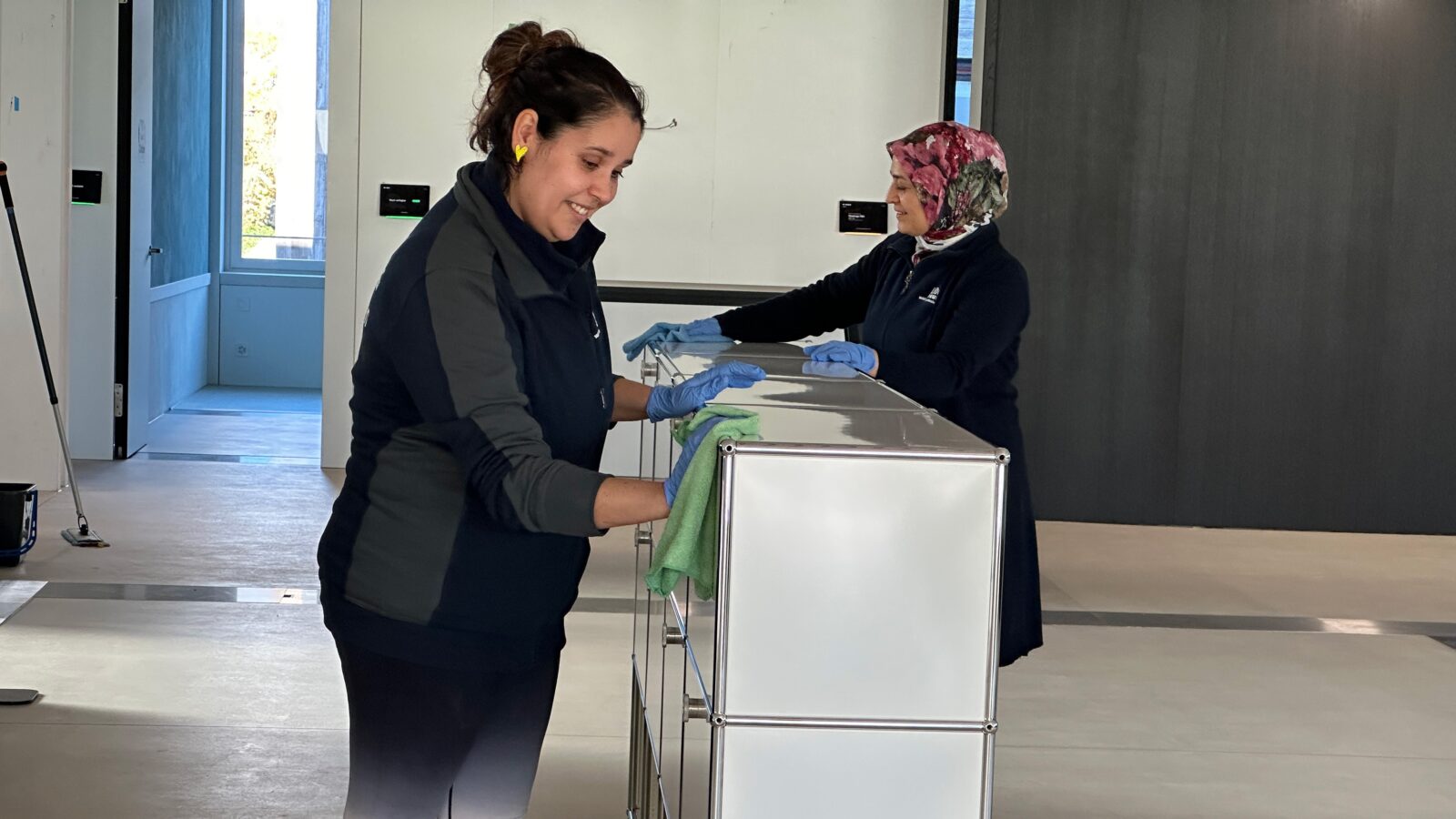 Zwei Mitarbeiterinnen des Läbesruums reinigen ein Büromöbel.