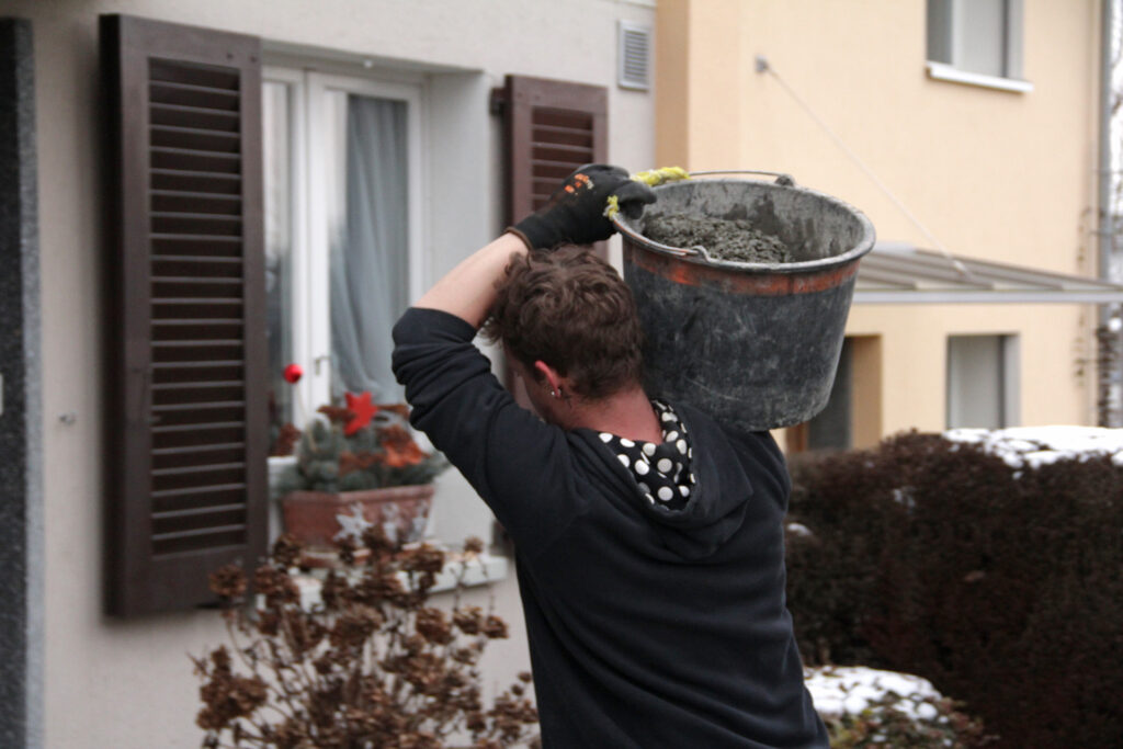 Mitarbeiter des Läbesruums trägt einen Zementkübel.