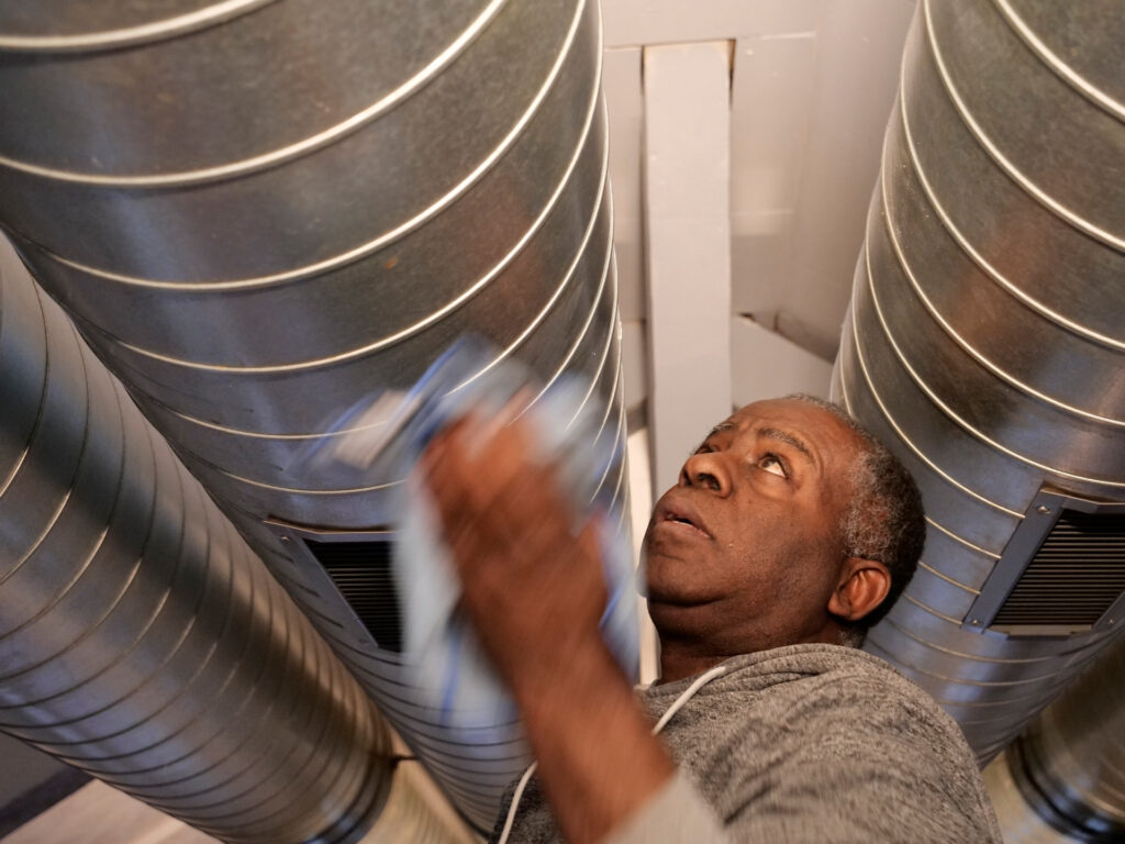 Mitarbeiter des Läbesruums reinigt eine Lüftungsanlage.