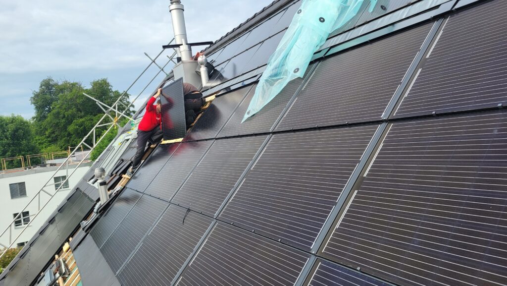 Zwei Mitarbeiter des Läbesruums montieren eine Indach-Solaranlage.