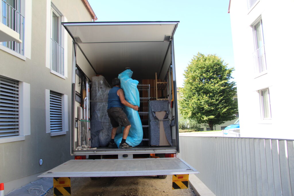 Ein Mitarbeiter des Läbesruums trägt eine Matratze in einen Umzugslastwagen.