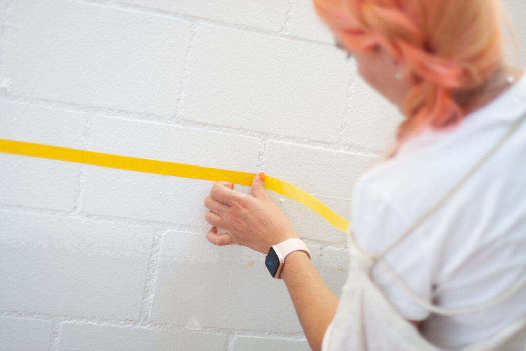 Eine Mitarbeiterin des Läbesruums klebt eine Wand ab.