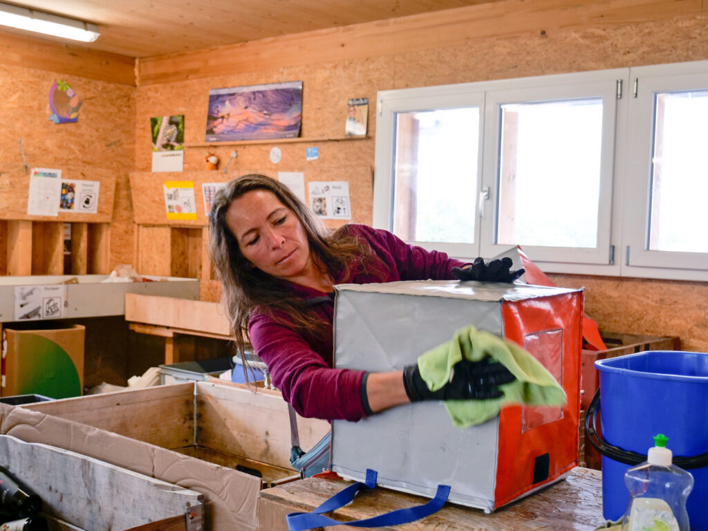 Eine Mitarbeiterin des Läbesruums reinigt Taschen des Recyclingabos.