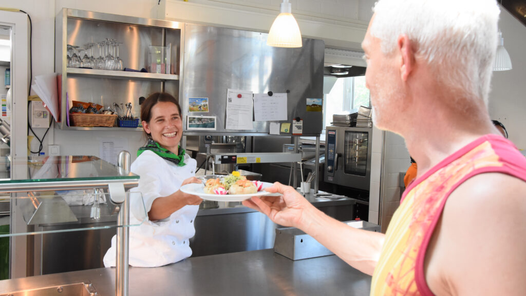 Eine Mitarbeiterin des Läbesruums serviert im Restaurant Eulachstrand einen Teller.