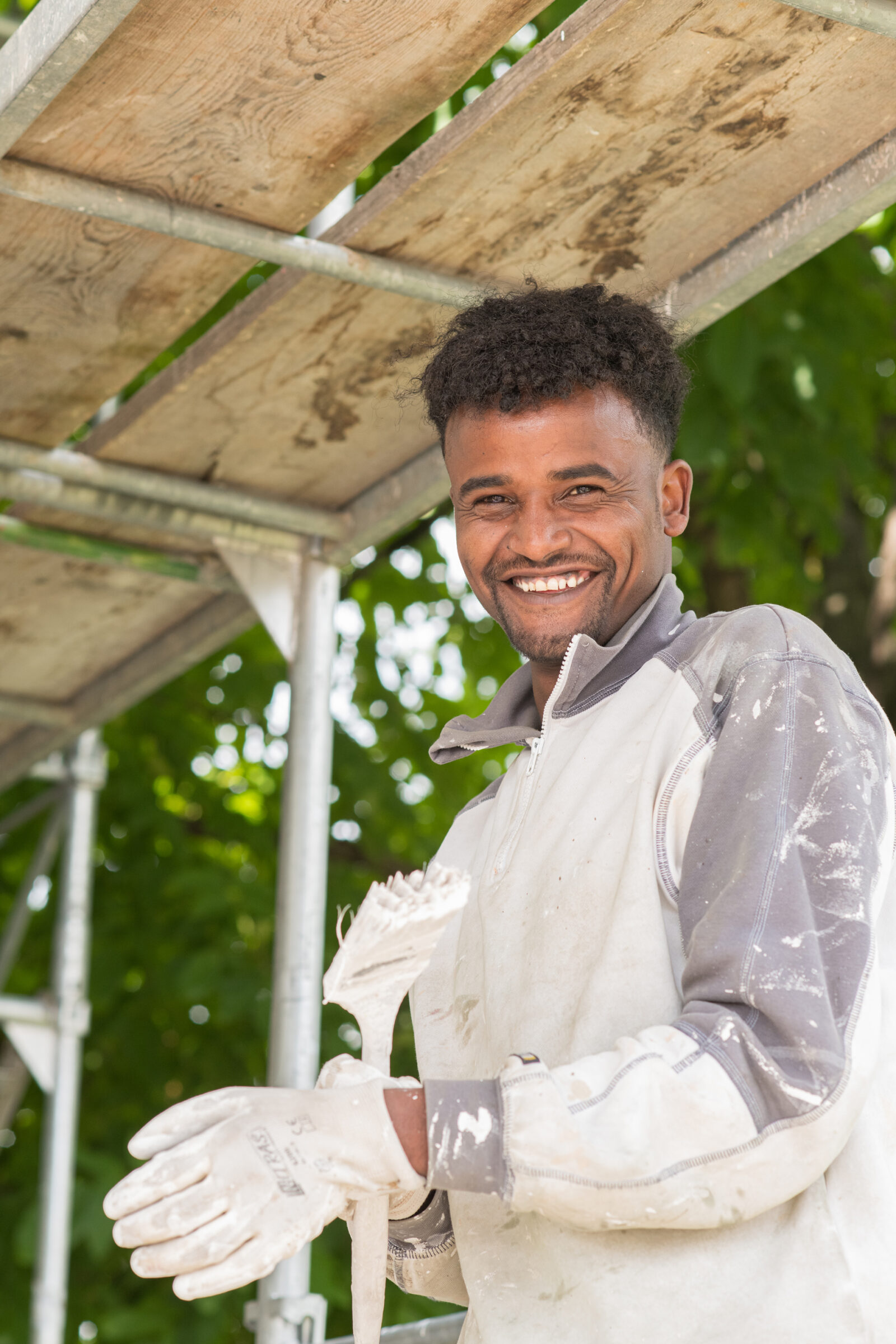 Ein Lernender des Läbesruums auf einem Baugerüst um eine Fassade zu malen.
