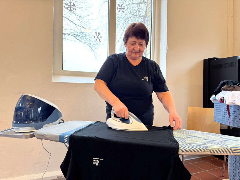 Mitarbeiterin des Läbesruums bügelt die Wäsche.