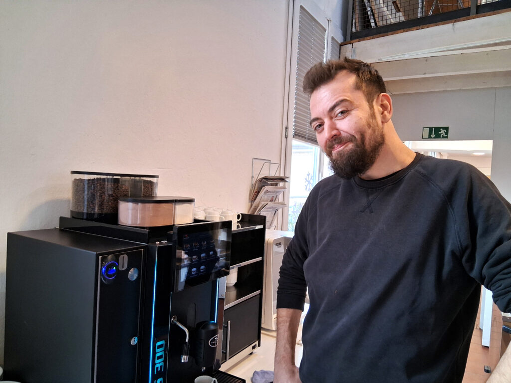 Burak, ein Mitarbeiter des Läbesruums, steht neben der Kaffeemaschine im Restaurant Eulachstrand.