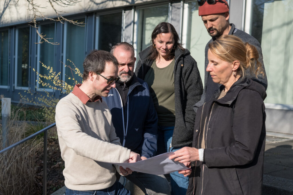Der Geschäftsführer und vier Bereichsleitende des Läbesruums schauen sich Pläne für das Umbauprojekt an der Palmstrasse an.