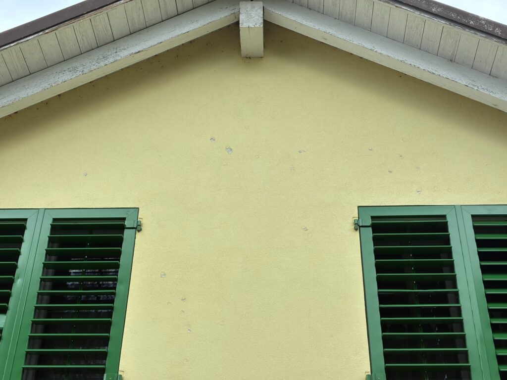 Fassade eines Einfamilienhaus mit Löchern nach einem Hagelsturm.